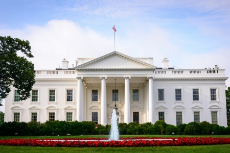[ai] The White House, a historic building in Washington, D.C., featuring its iconic white faÃ§ade, columns, and lush green gardens with a fountain in the foreground and red flower beds.